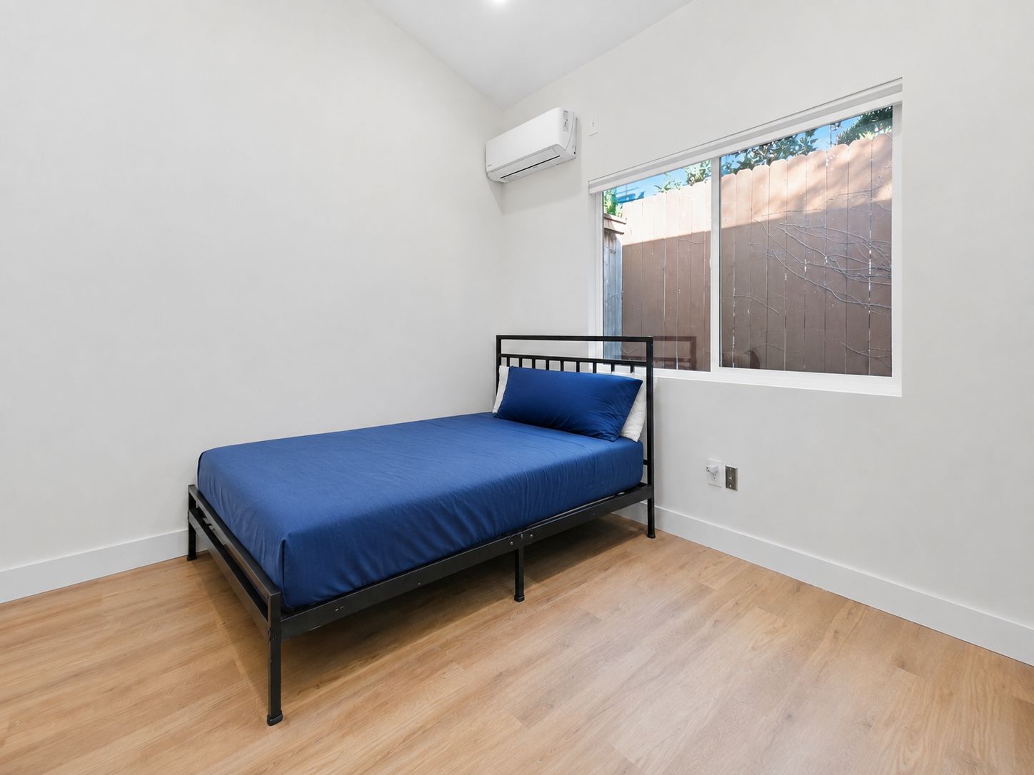 Second bedroom with mini-split unit and yard view