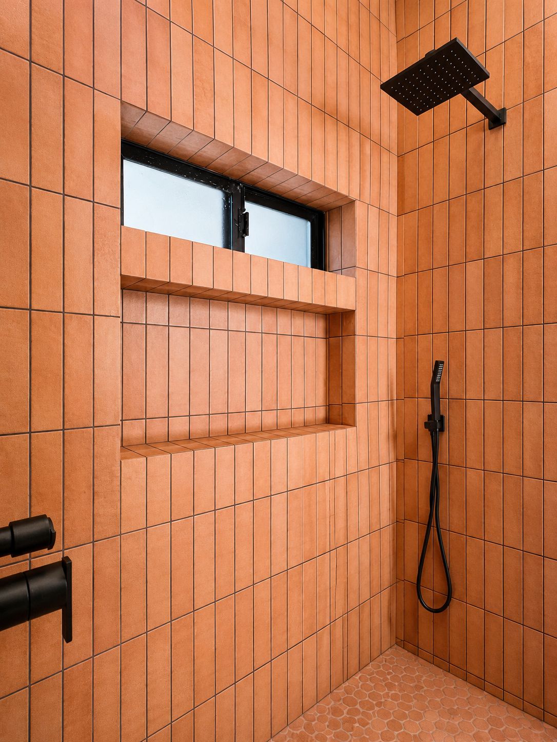 Bathroom shower with terracotta tile and black fixtures