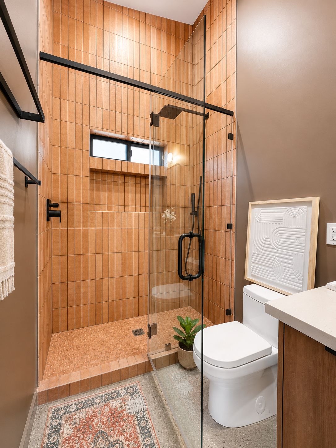 Glass-enclosed shower with terracotta tile and window nook