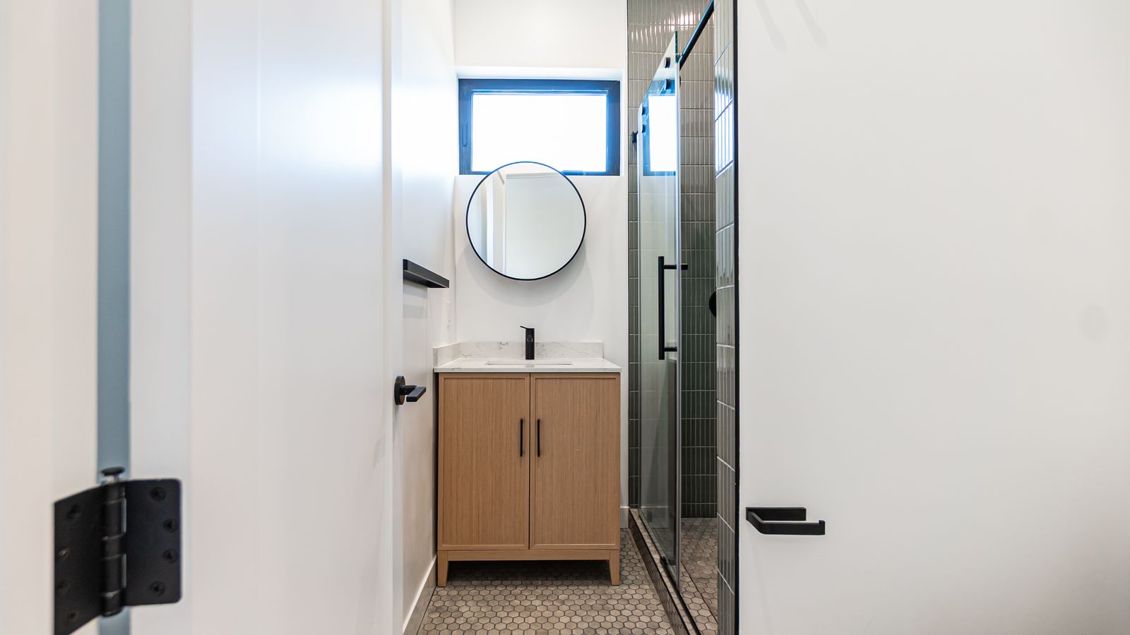 Bathroom vanity view with tiled shower and window