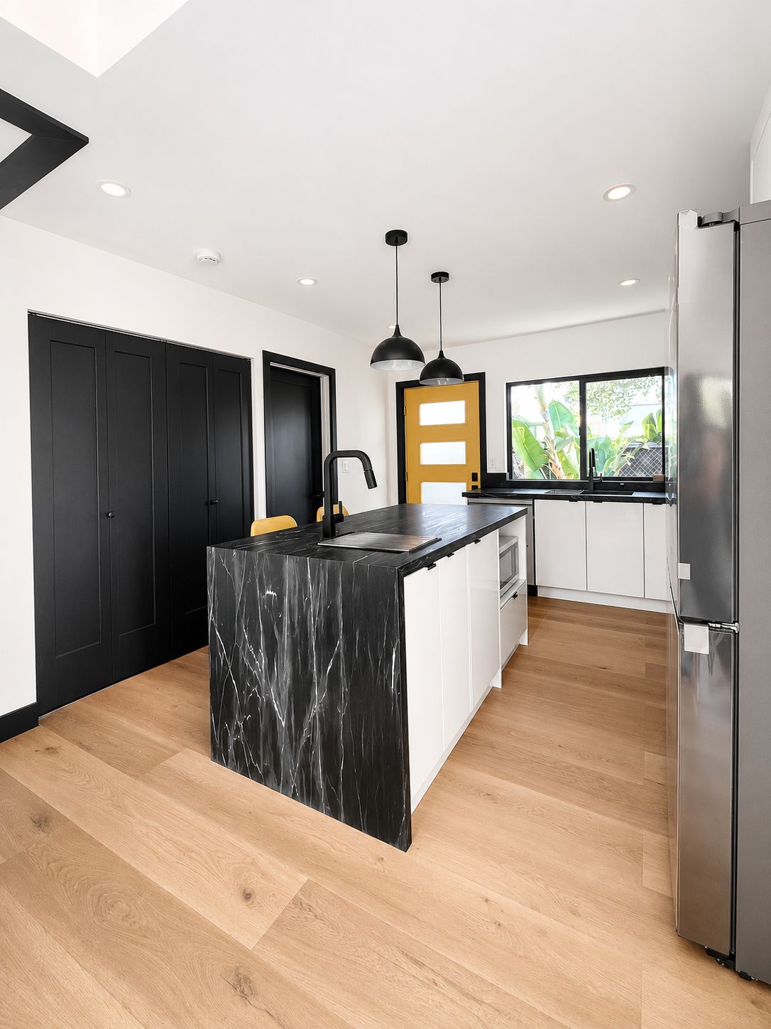 Kitchen with black cabinetry and yellow front door in the background
