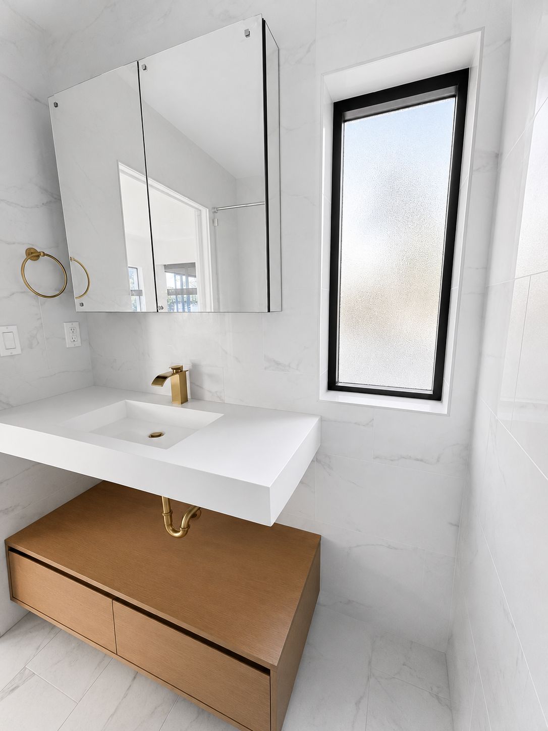 Bathroom vanity with marble walls and gold fixtures