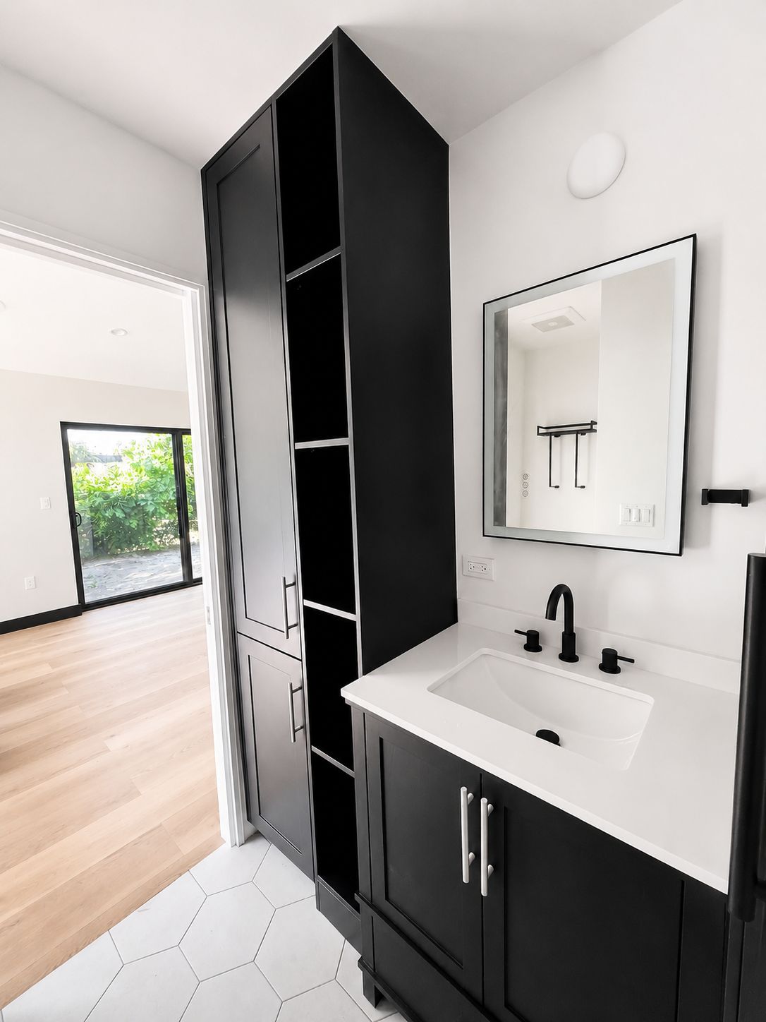 Bathroom vanity with black cabinetry and tall linen storage