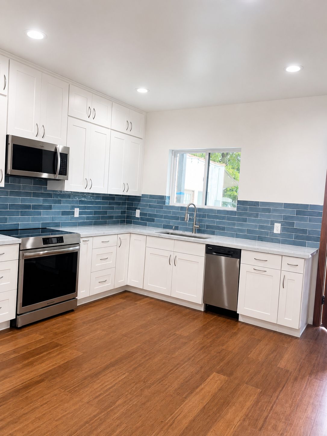 Kitchen backsplash detail with blue subway tile and marble counters