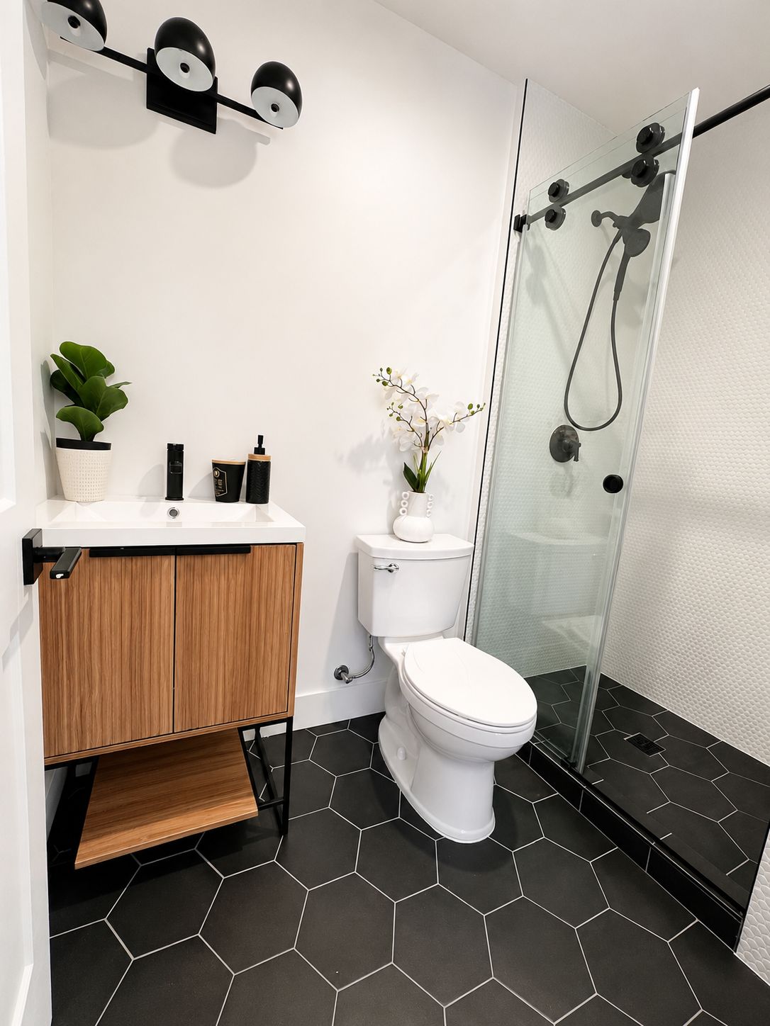 Finished bathroom with black hexagon tile and glass shower